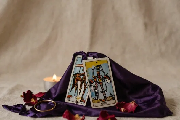 Dos anillos, pétalos y cartas sobre una tela violeta como composición simbólica del amor