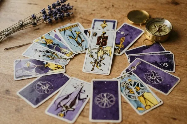 Diez cartas de tarot dispuestas en cruz celta sobre madera de roble, vistas desde arriba